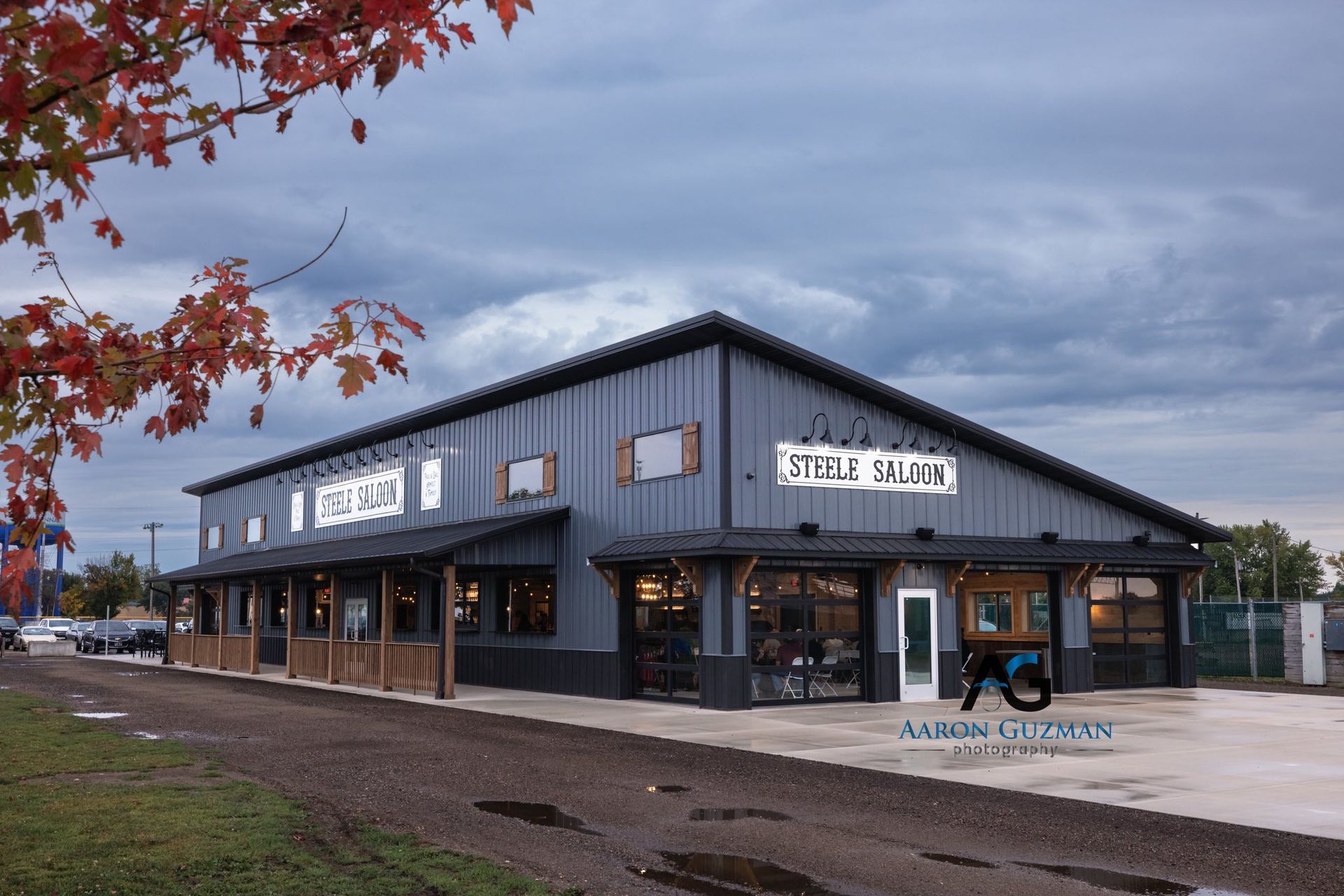 Saloon building with a covered porch and sign, cloudy sky, fall foliage.