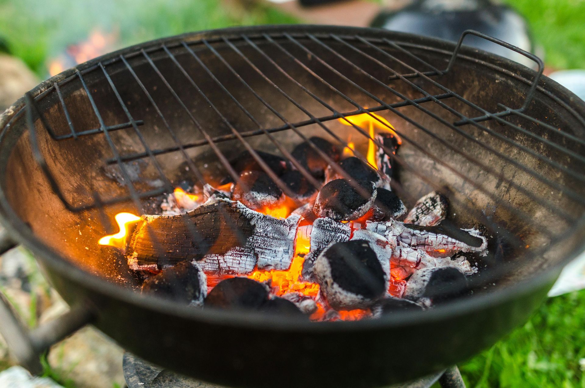 Charcoal grill with glowing embers and flames burning inside an open round fire pit