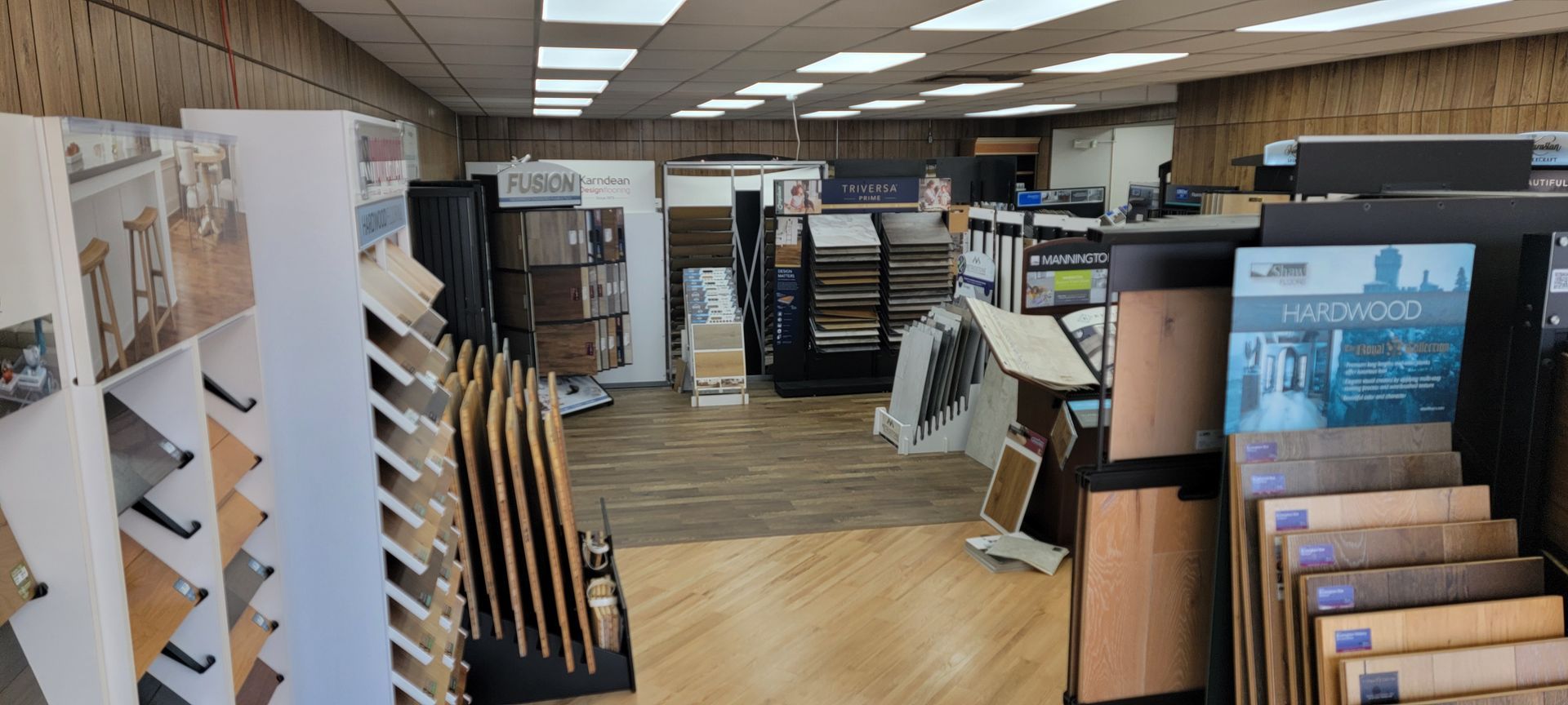 Tile showroom with display racks of flooring samples and cabinets under fluorescent lights