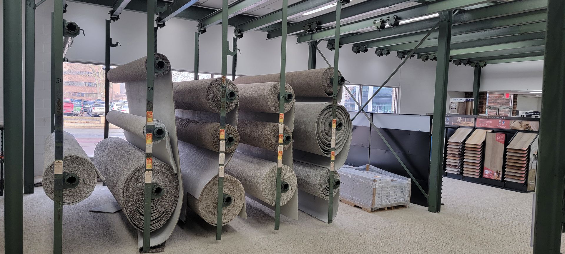 Rolls of carpet on display racks in a warehouse. Spools of fiber and stacked materials in an industrial warehouse room