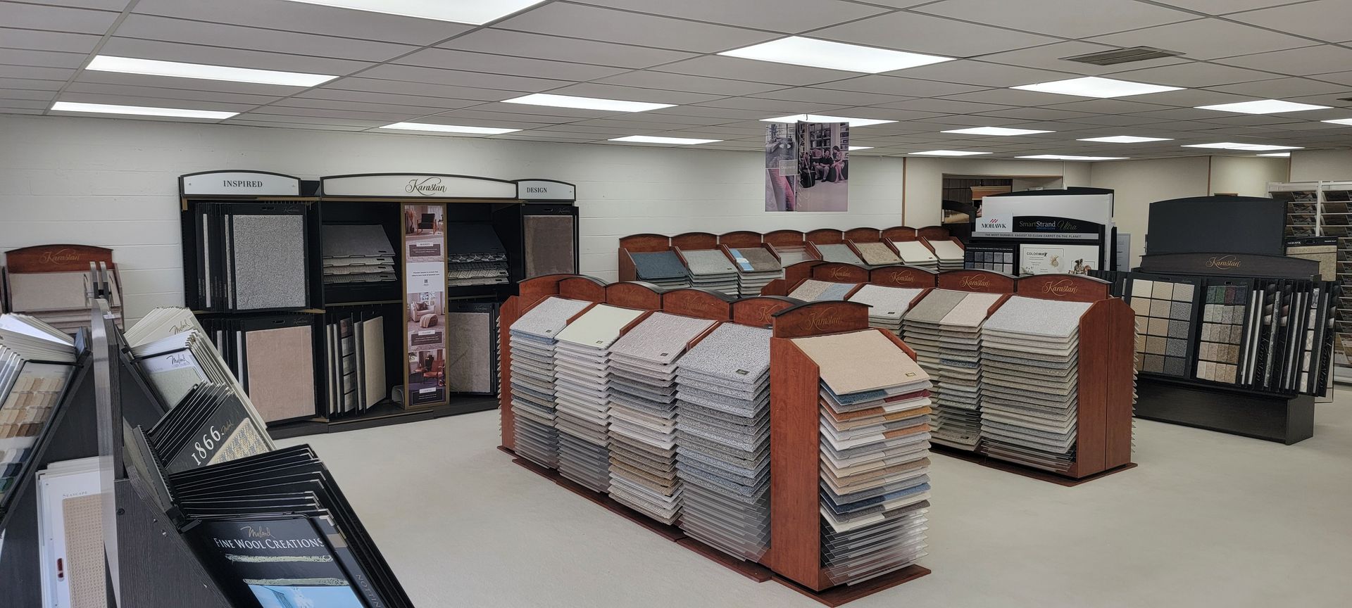 Interior of a tile showroom, featuring various tile displays and overhead lighting. Store interior with rows of beds and mattresses in a showroom display, under bright ceiling lights