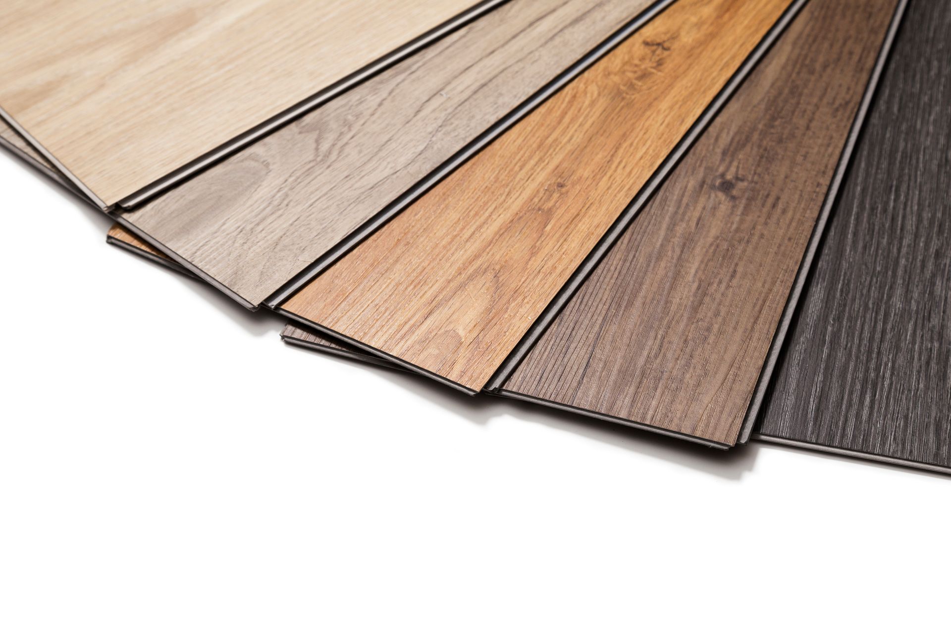 Samples of various wood-look laminate flooring colors, arranged in a fan shape. Sample wood-look flooring planks in light to dark brown shades, fanned out on white background