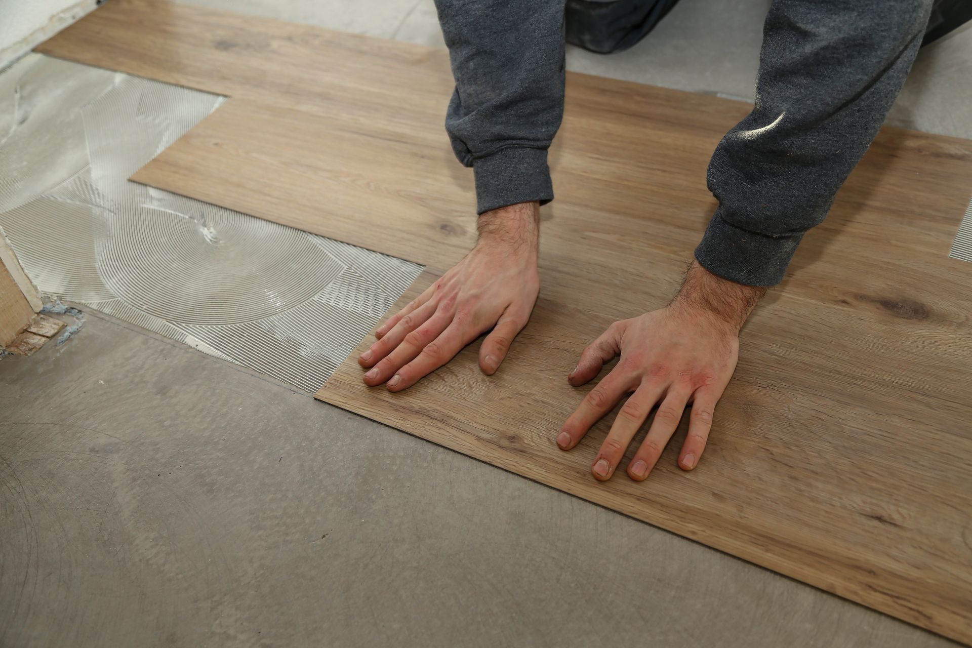 Person installing wood flooring over adhesive on a subfloor