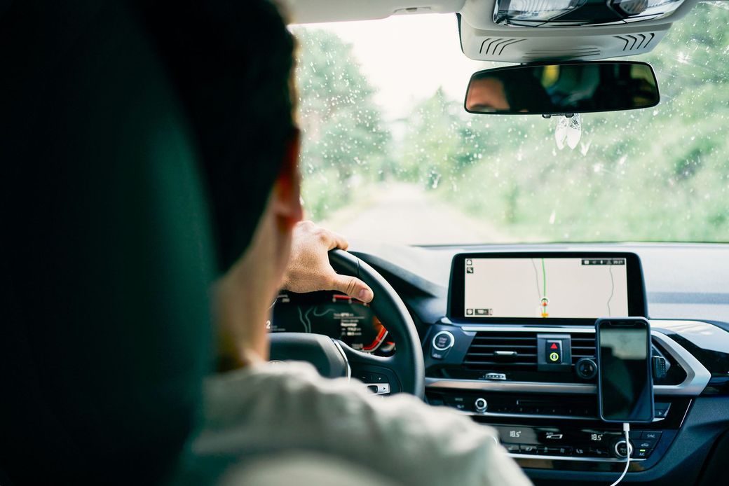 Un uomo sta guidando un'auto su una strada.