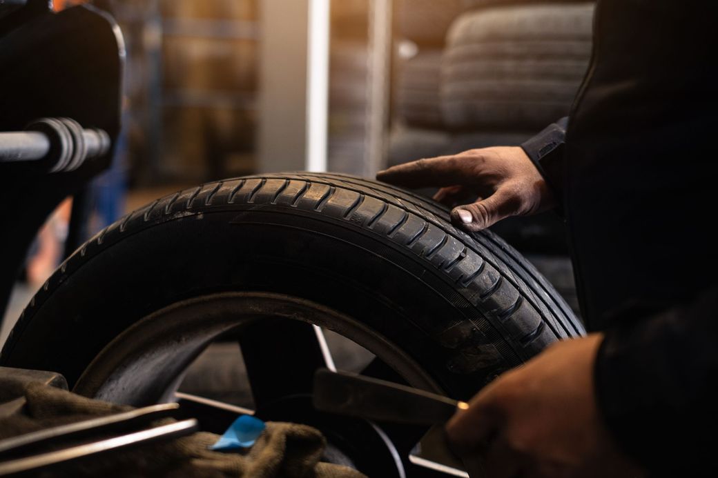 Un uomo sta bilanciando uno pneumatico su una ruota in un garage.