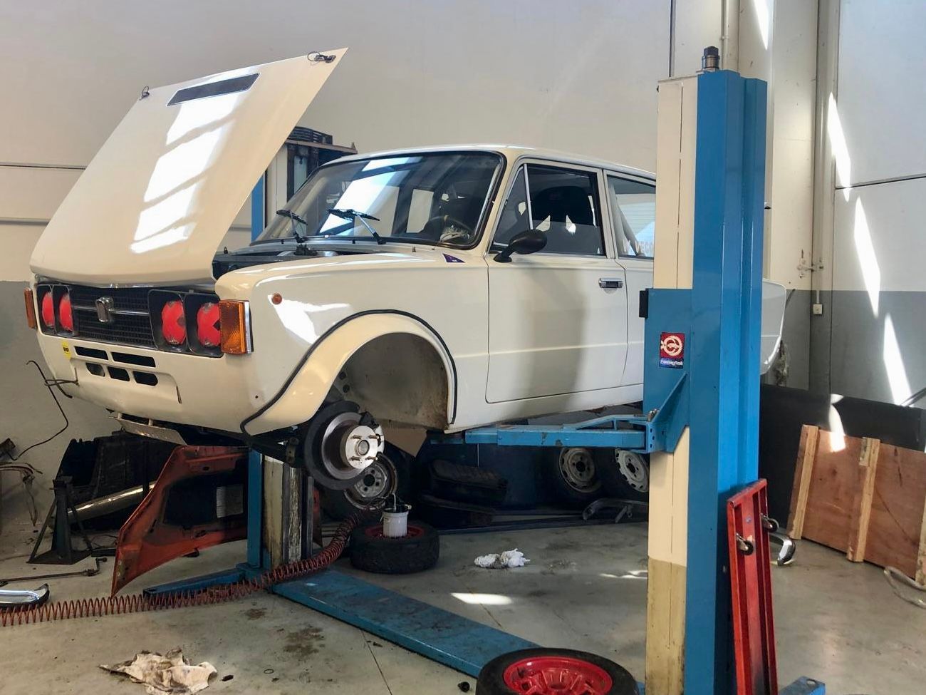 Un'auto bianca è parcheggiata su un ponte elevatore in un garage.