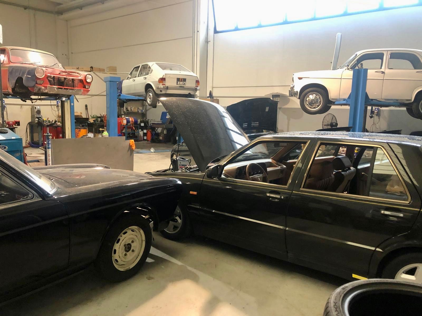 Una fila di auto sono parcheggiate in un garage con i cofani aperti.