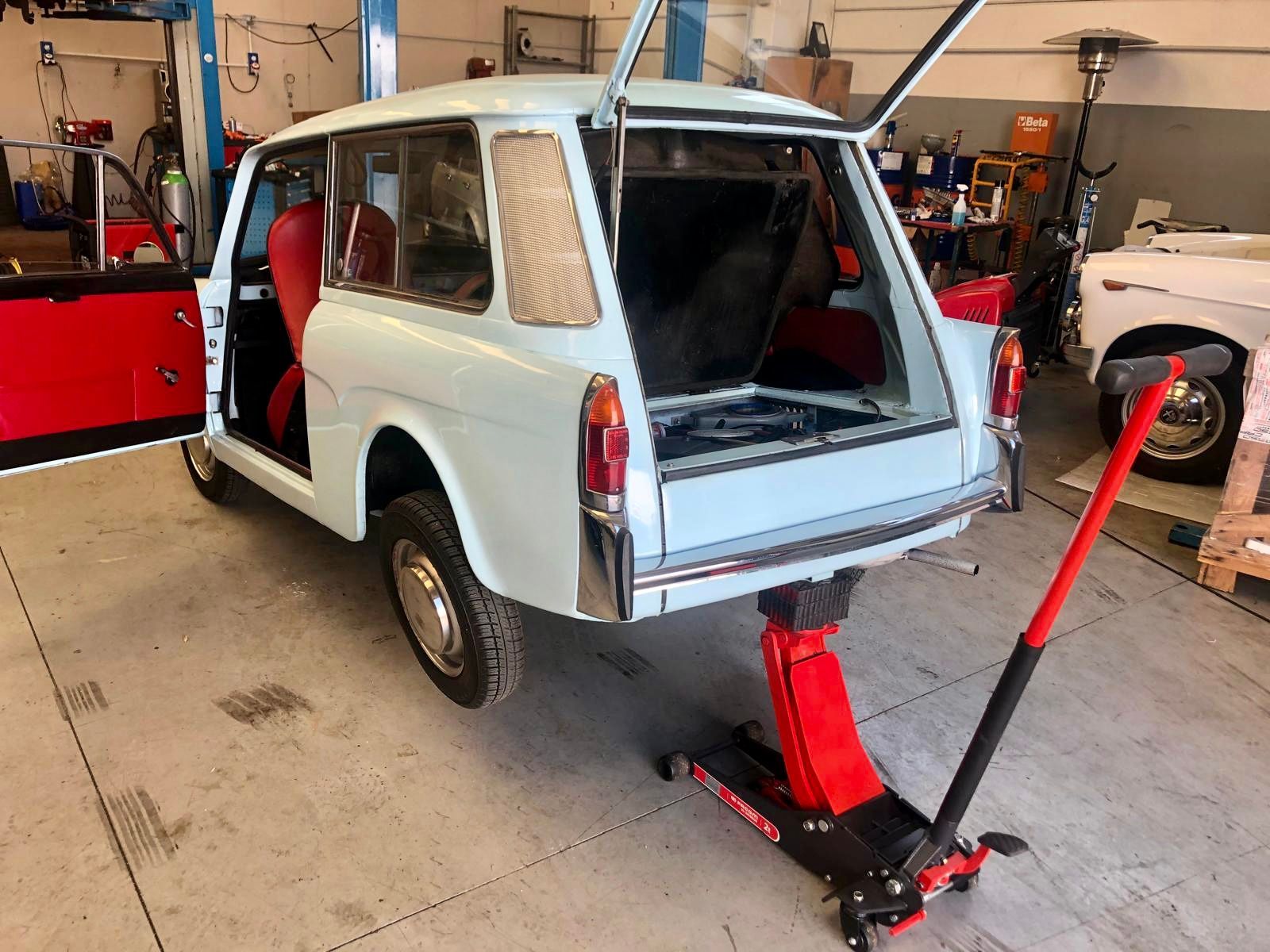Un'auto è appoggiata su un cric in un garage.
