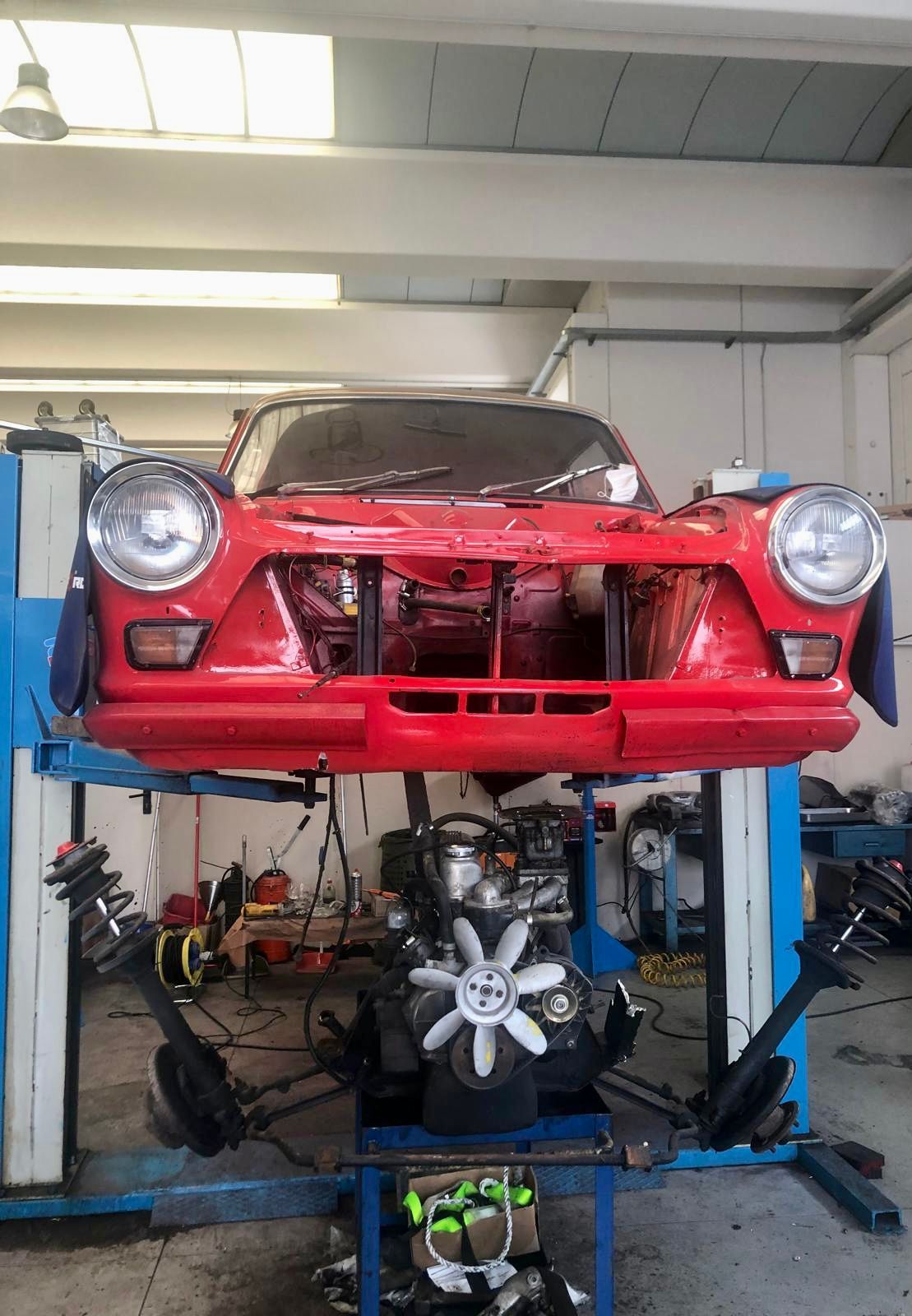 Un'auto rossa è parcheggiata sopra un ascensore blu in un garage.
