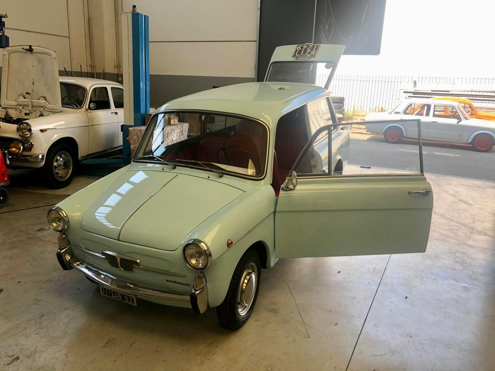 Una vecchia macchina è parcheggiata in un garage con le portiere aperte.