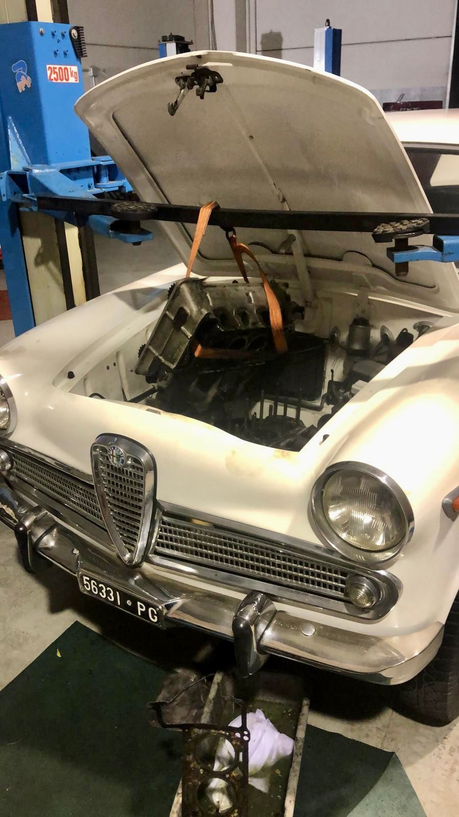 Un'auto bianca con il cofano aperto in un garage.
