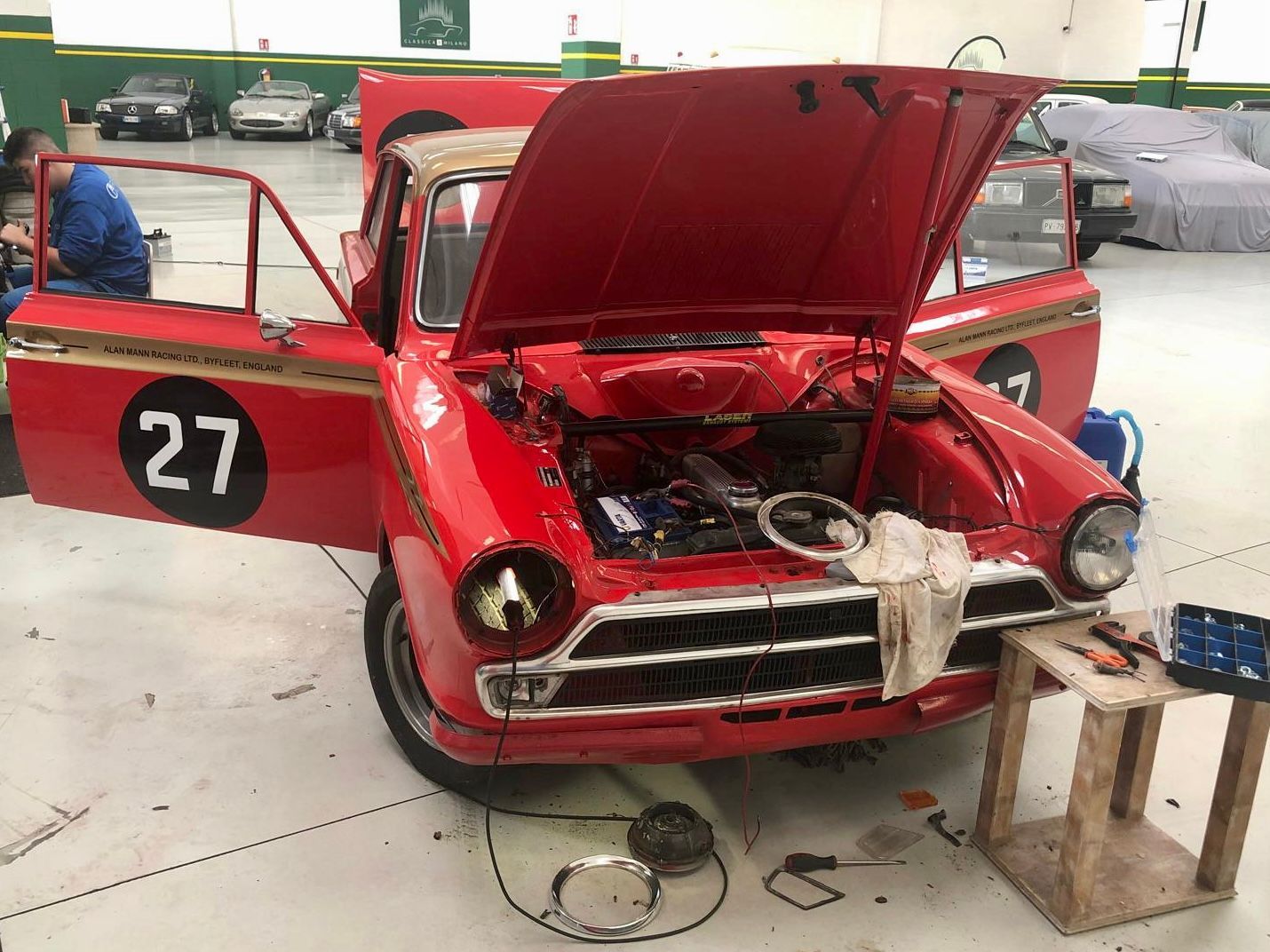 Un'auto rossa con il numero 27 sulla fiancata è in fase di lavorazione in un garage.