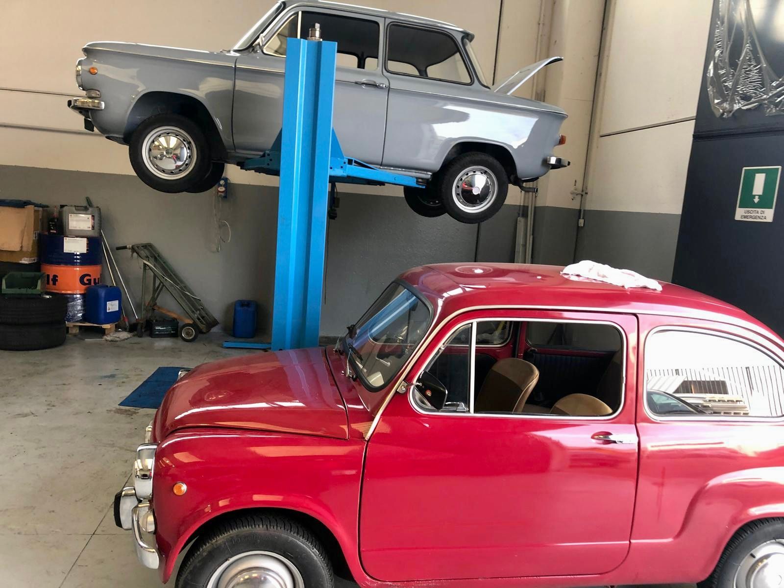 Un'auto rossa è parcheggiata accanto a un'auto grigia su un ascensore in un garage.