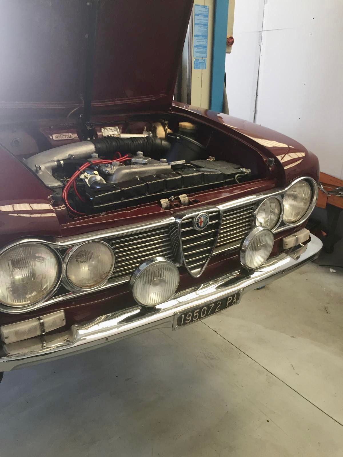 Un'auto rossa con il cofano aperto è parcheggiata in un garage.