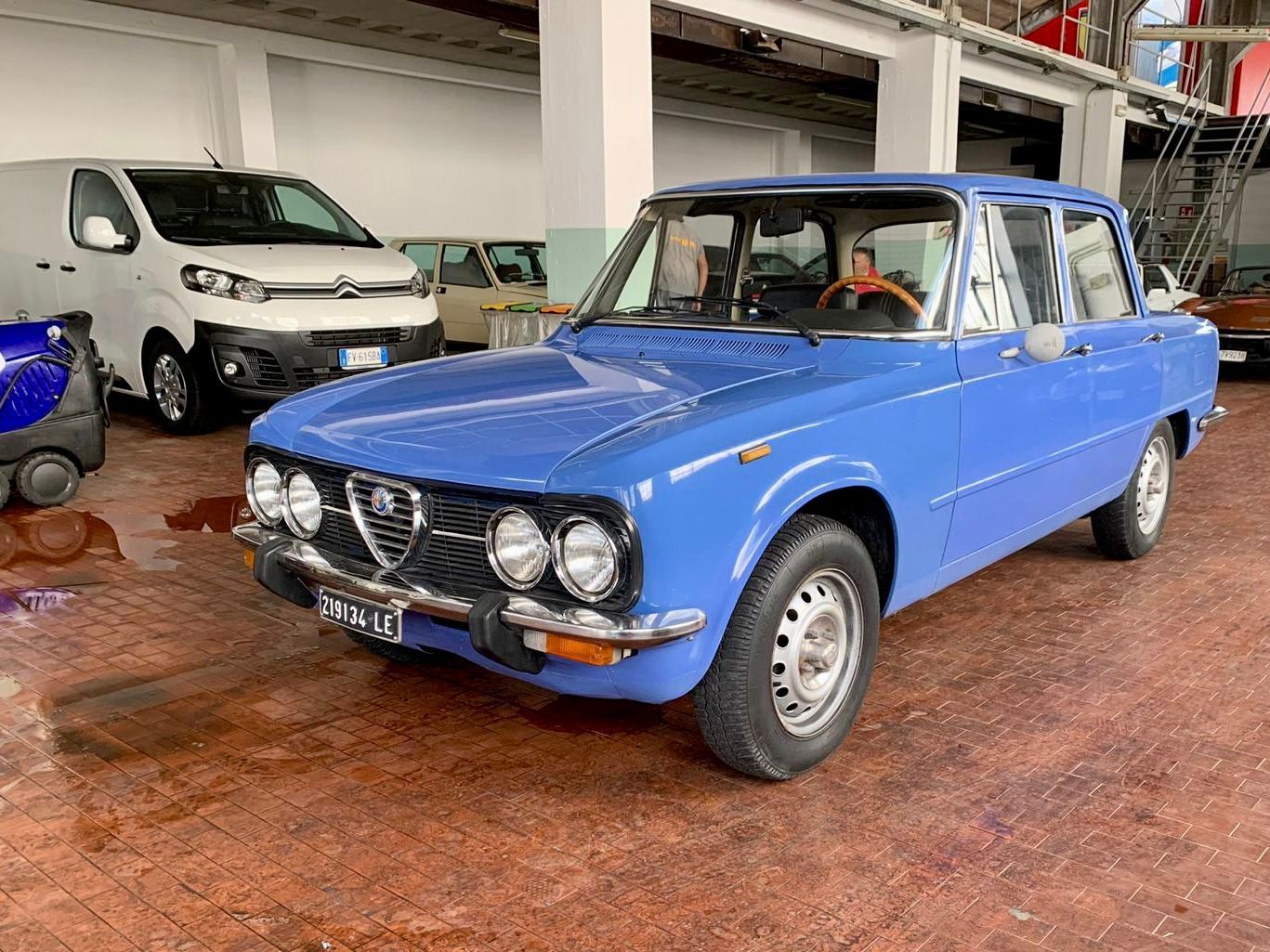 Un'auto blu è parcheggiata in un garage accanto a un furgone bianco.