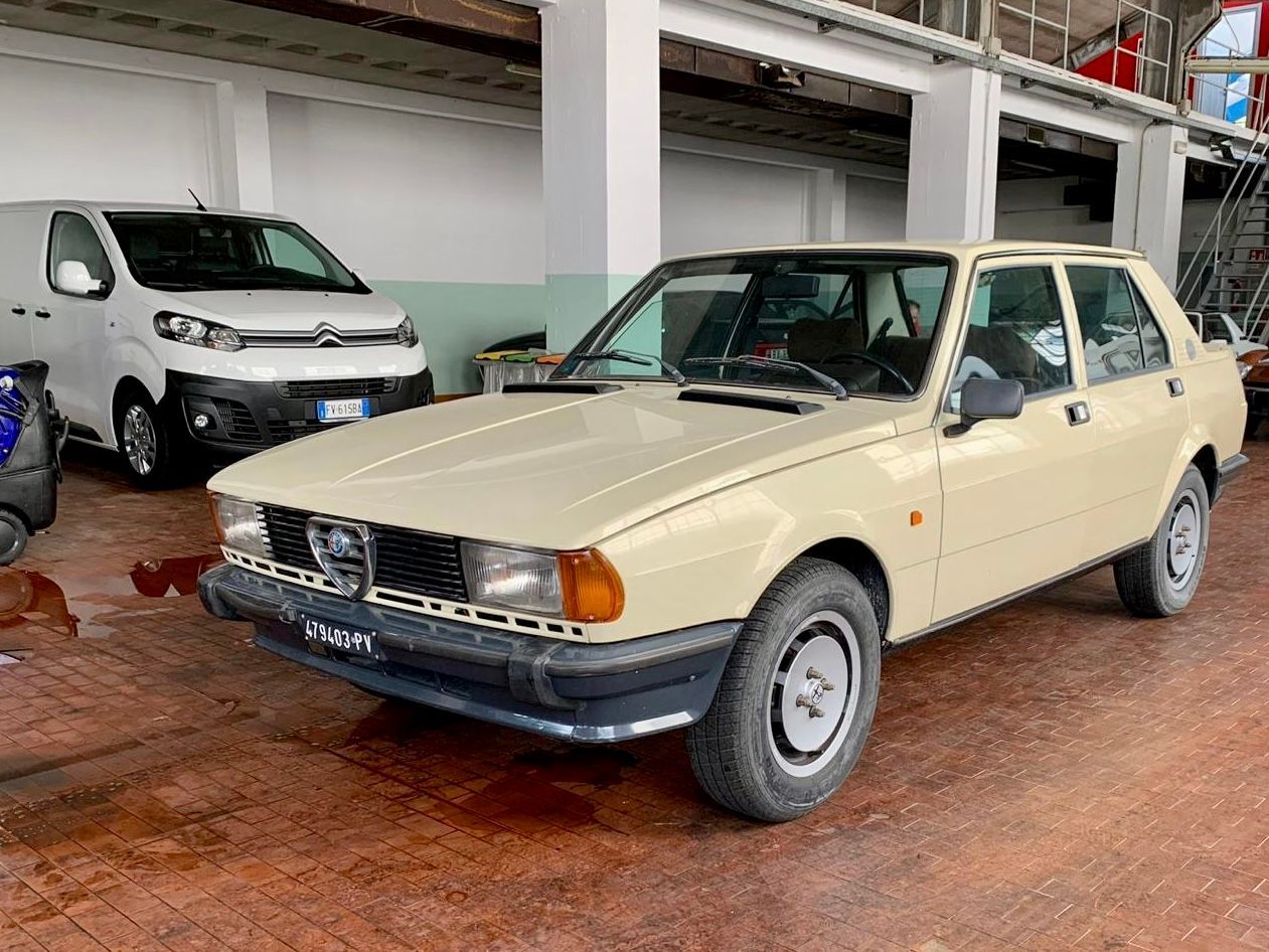 Un'auto beige è parcheggiata in un garage accanto a un furgone bianco.