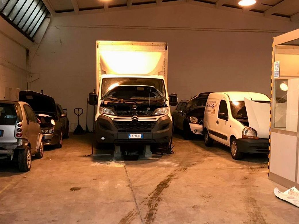 Una fila di furgoni sono parcheggiati in un garage con i cofani aperti