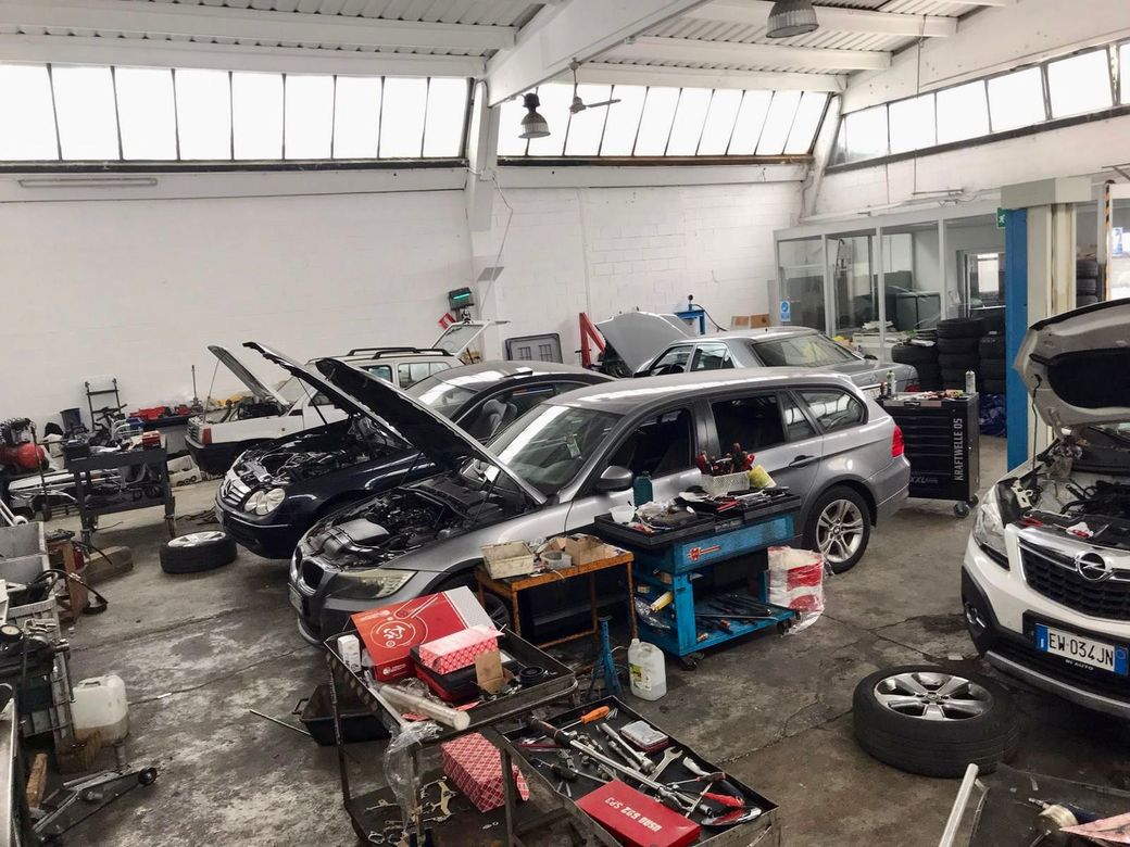 Un garage pieno di auto con il cofano aperto.