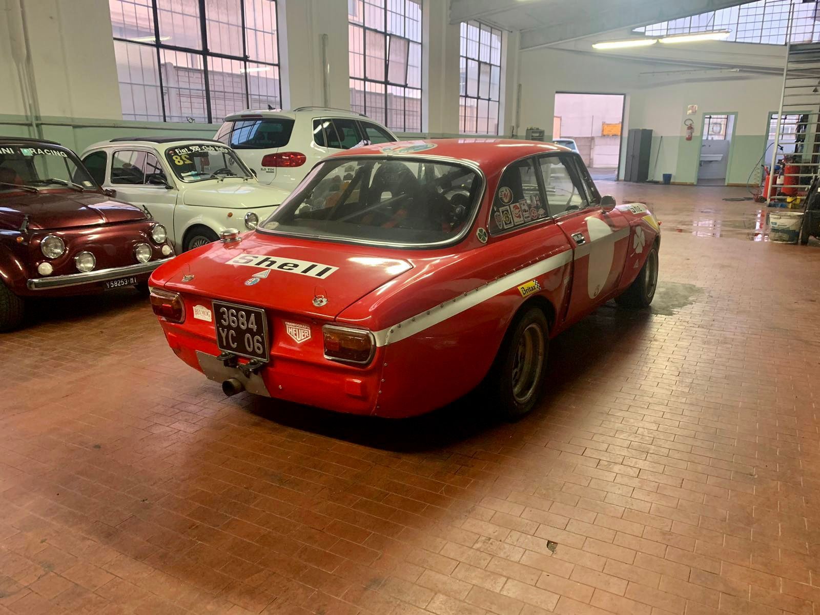 Un'auto rossa è parcheggiata in un garage accanto ad altre auto.