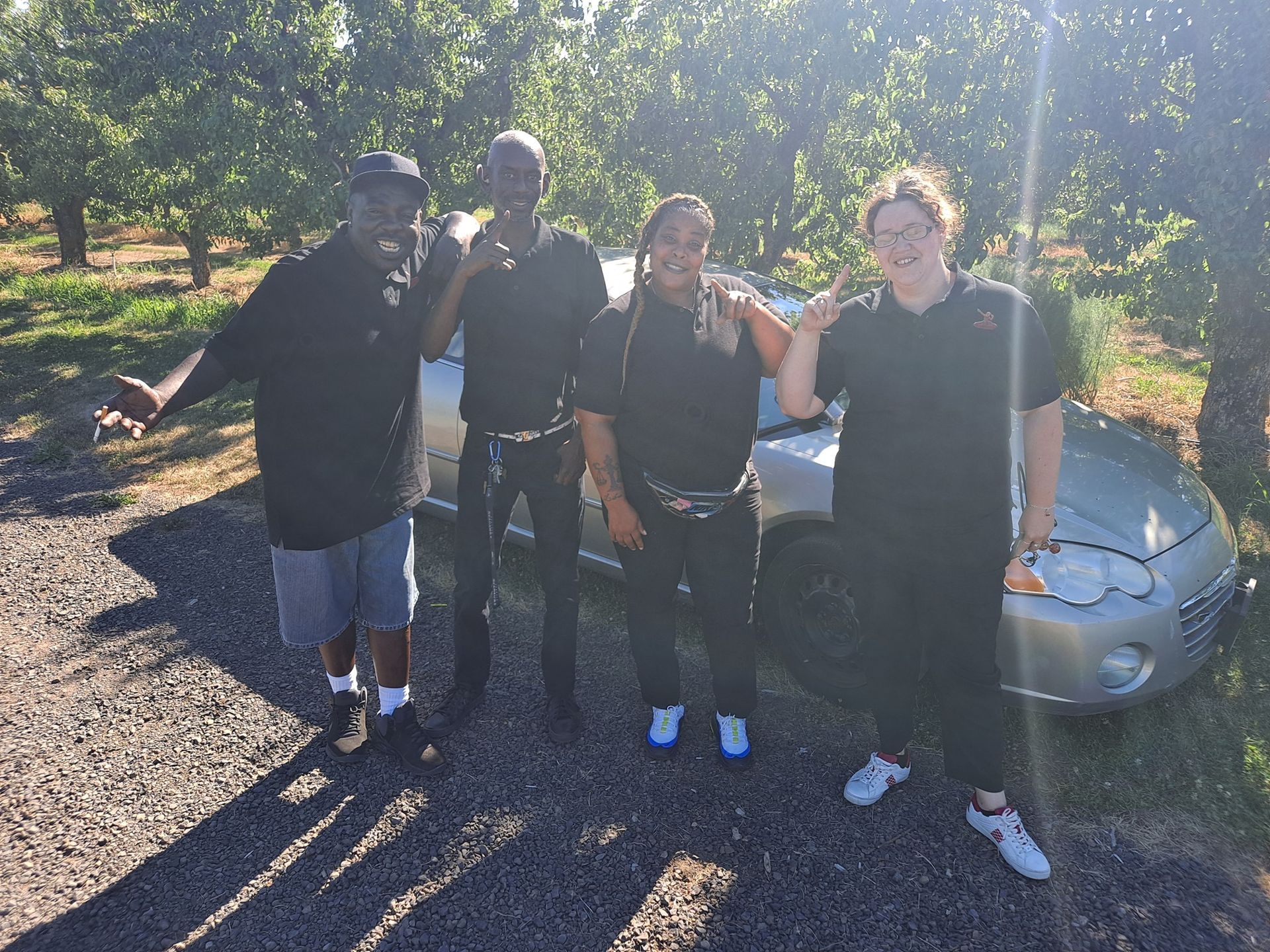 A group of people are posing for a picture in front of a car.