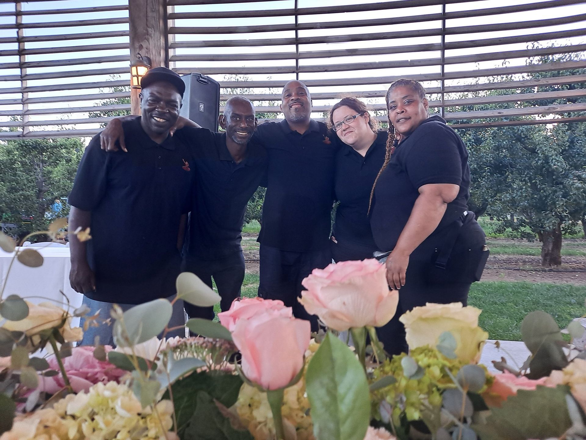 A group of people are posing for a picture in front of flowers.