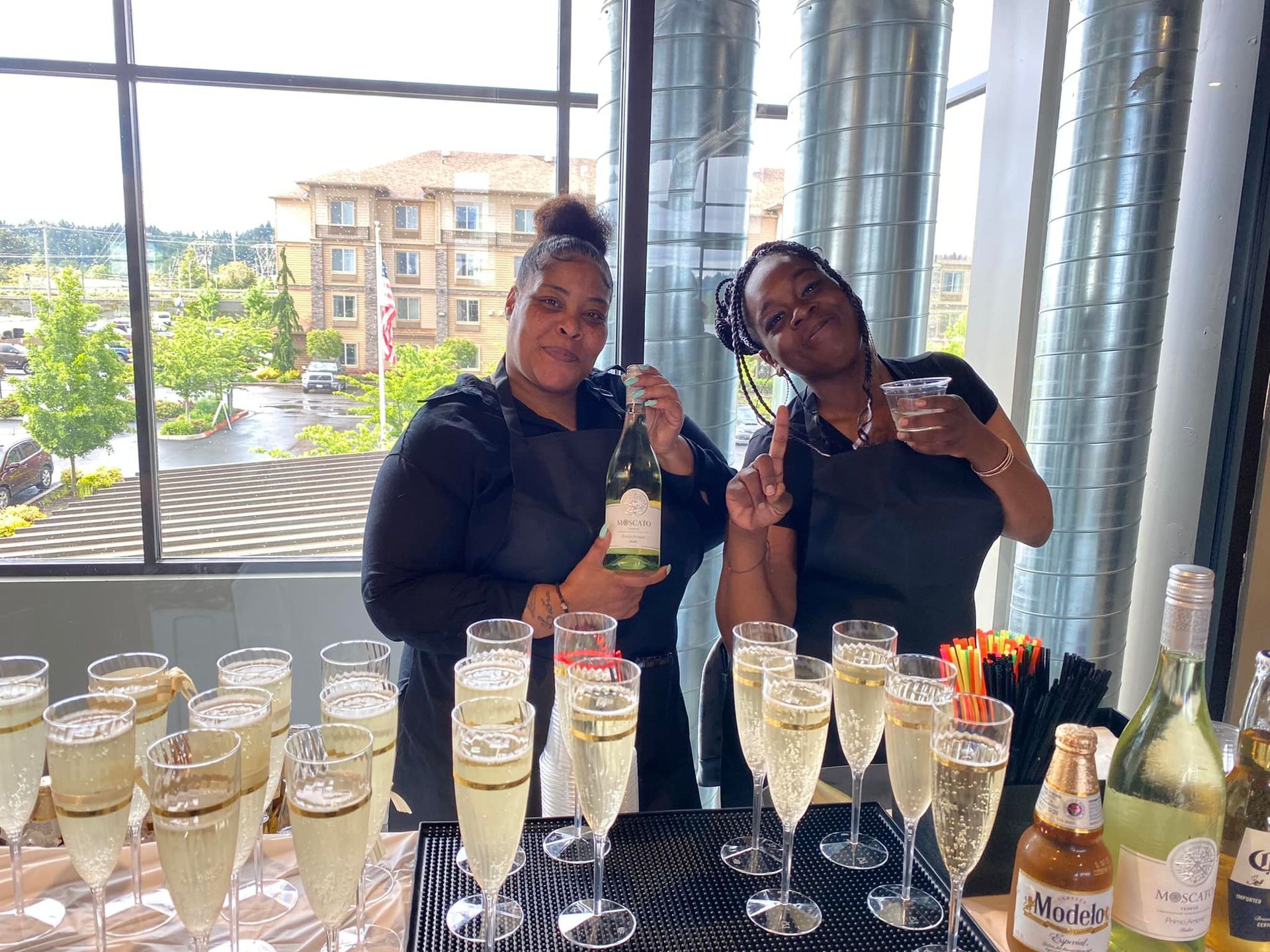 Two women are standing next to each other holding bottles of champagne and glasses of champagne.
