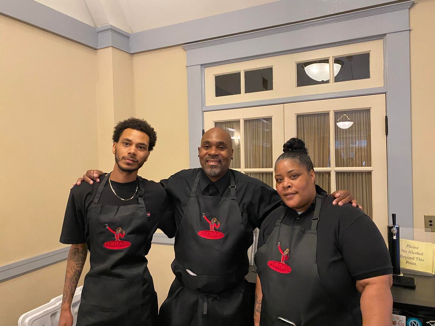 Three people wearing aprons are posing for a picture in a room.