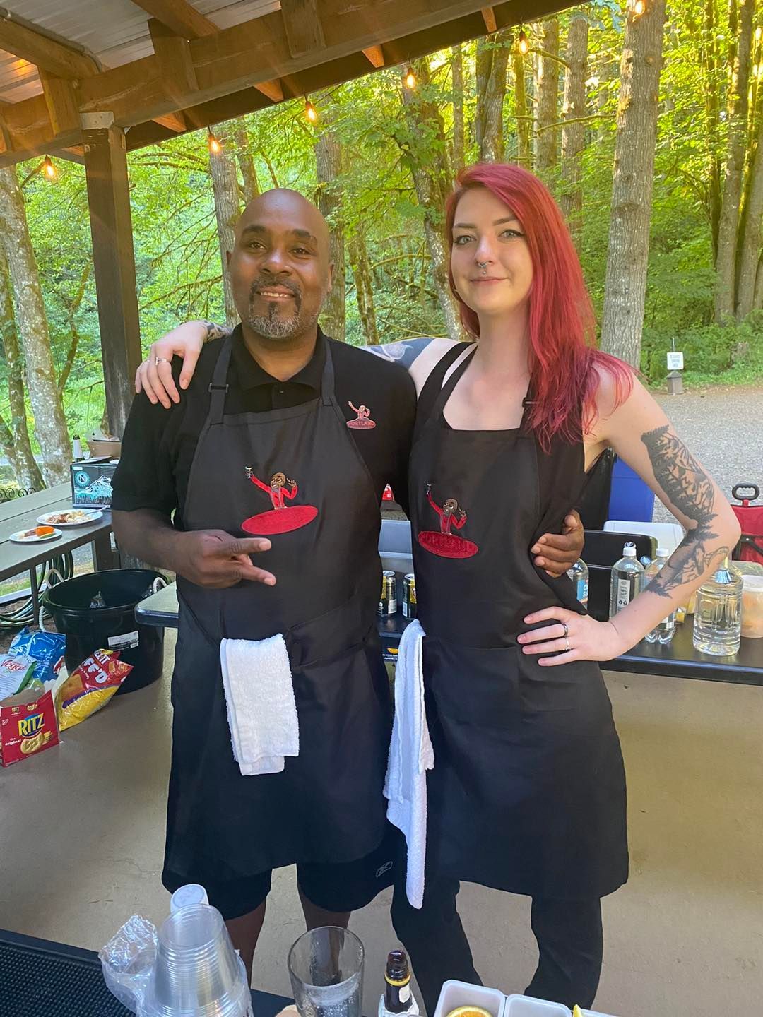 A man and a woman are posing for a picture while wearing aprons.