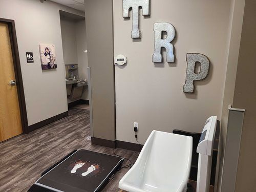 Hallway in a medical facility with a treadmill, changing station, and the word