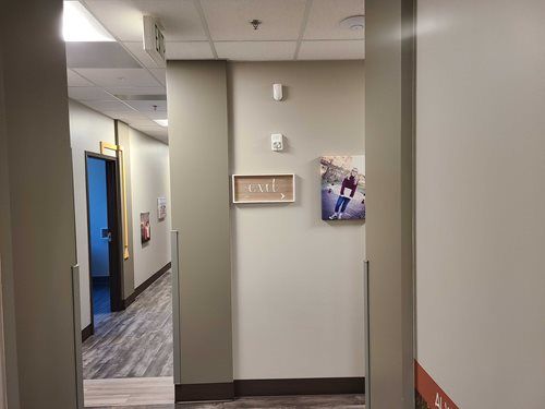Hallway with gray walls, artwork, and a partially open door.