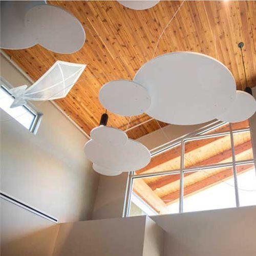 White cloud-shaped decorations hang from a wood ceiling near a window.