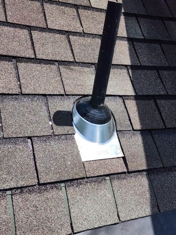 Rooftop vent pipe with metal flashing on gray shingle roof