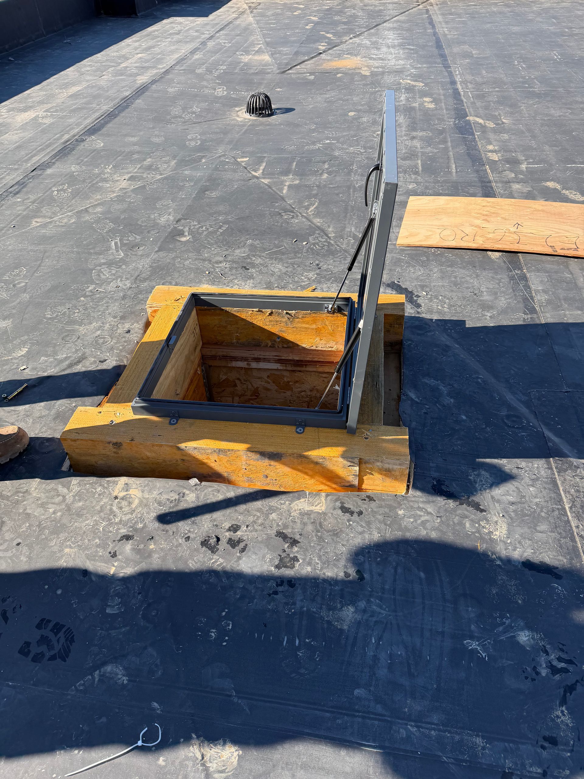Broken manhole cover with bent metal frame and wooden planks on a paved road