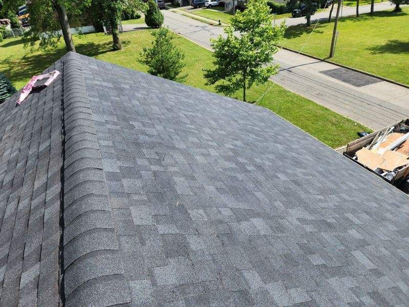 New gray shingle roof with a street and green lawn in the background