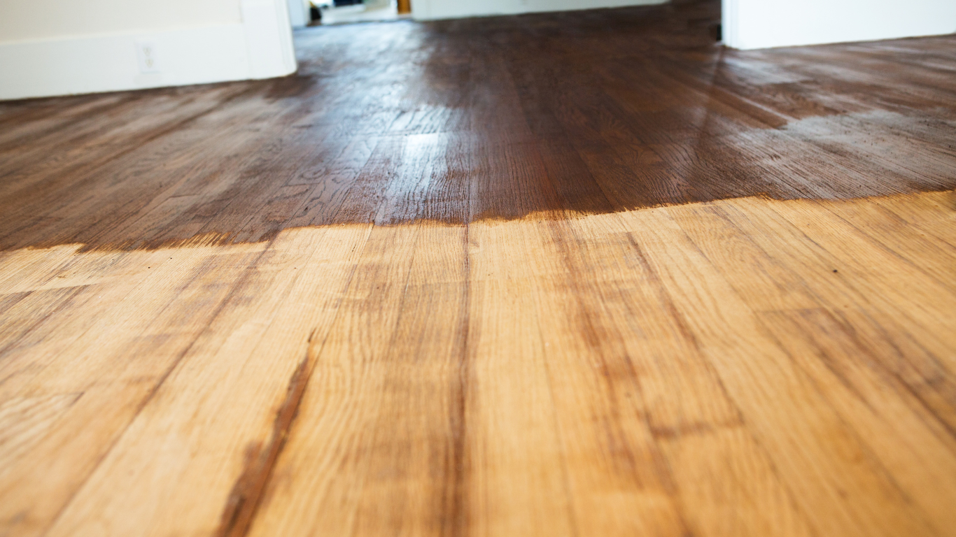A wooden floor is being painted in a room.