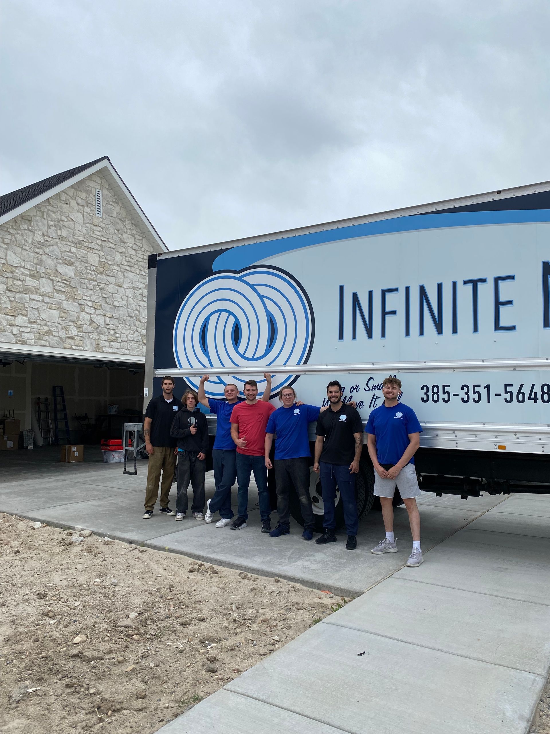 Group of men stand in front of a moving truck with the company logo 