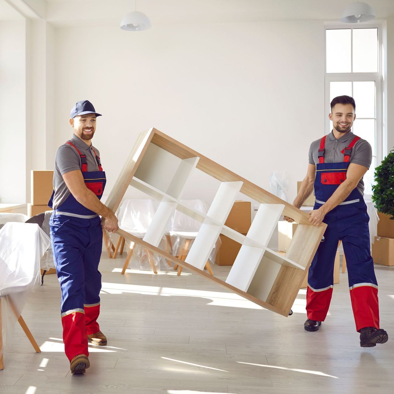 two men are carrying a shelf in a room .