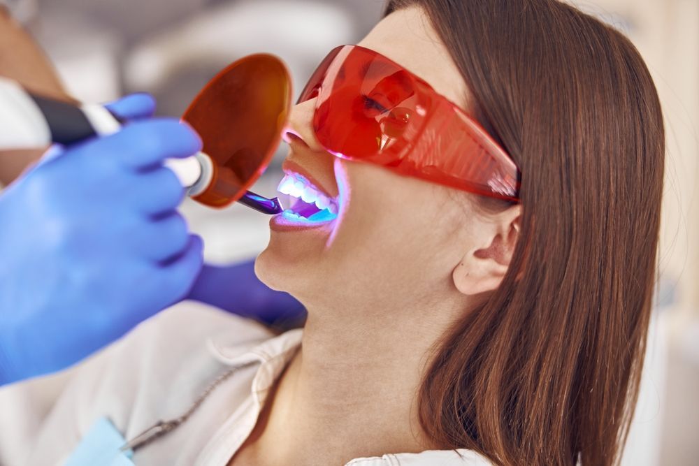 A Woman Is Getting Her Teeth Whitened By A Dentist — Mittagong Dental Care In Mittagong, NSW