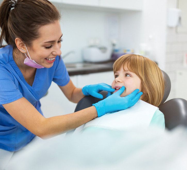 A Female Dentist Is Examining A Little Girl's Teeth In A Dental Chair — Mittagong Dental Care In Mittagong, NSW