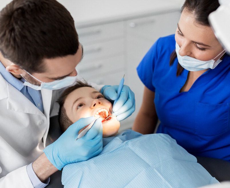 A Child Is Getting His Teeth Examined By A Dentist And A Nurse — Mittagong Dental Care In Mittagong, NSW