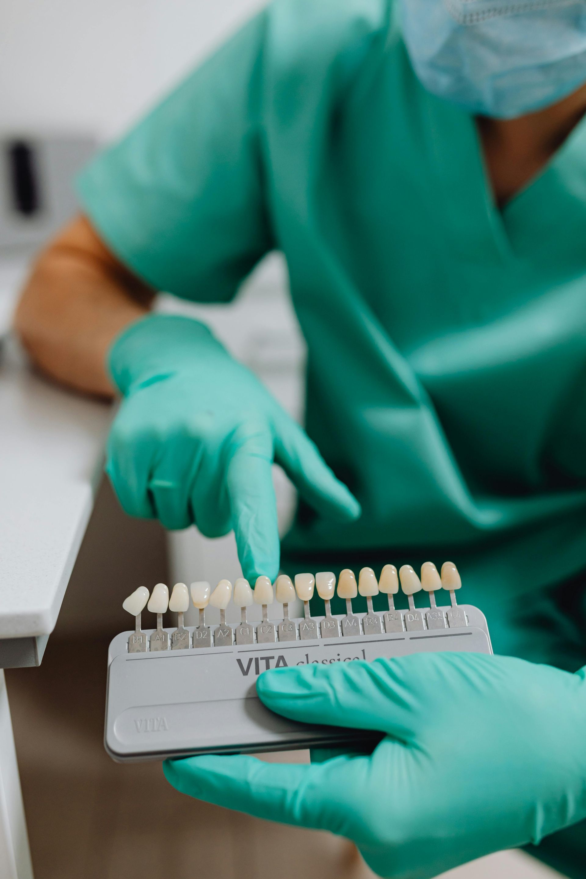 A Dentist Is Holding A Tray Of Teeth And Pointing At Them — Mittagong Dental Care In Mittagong, NSW