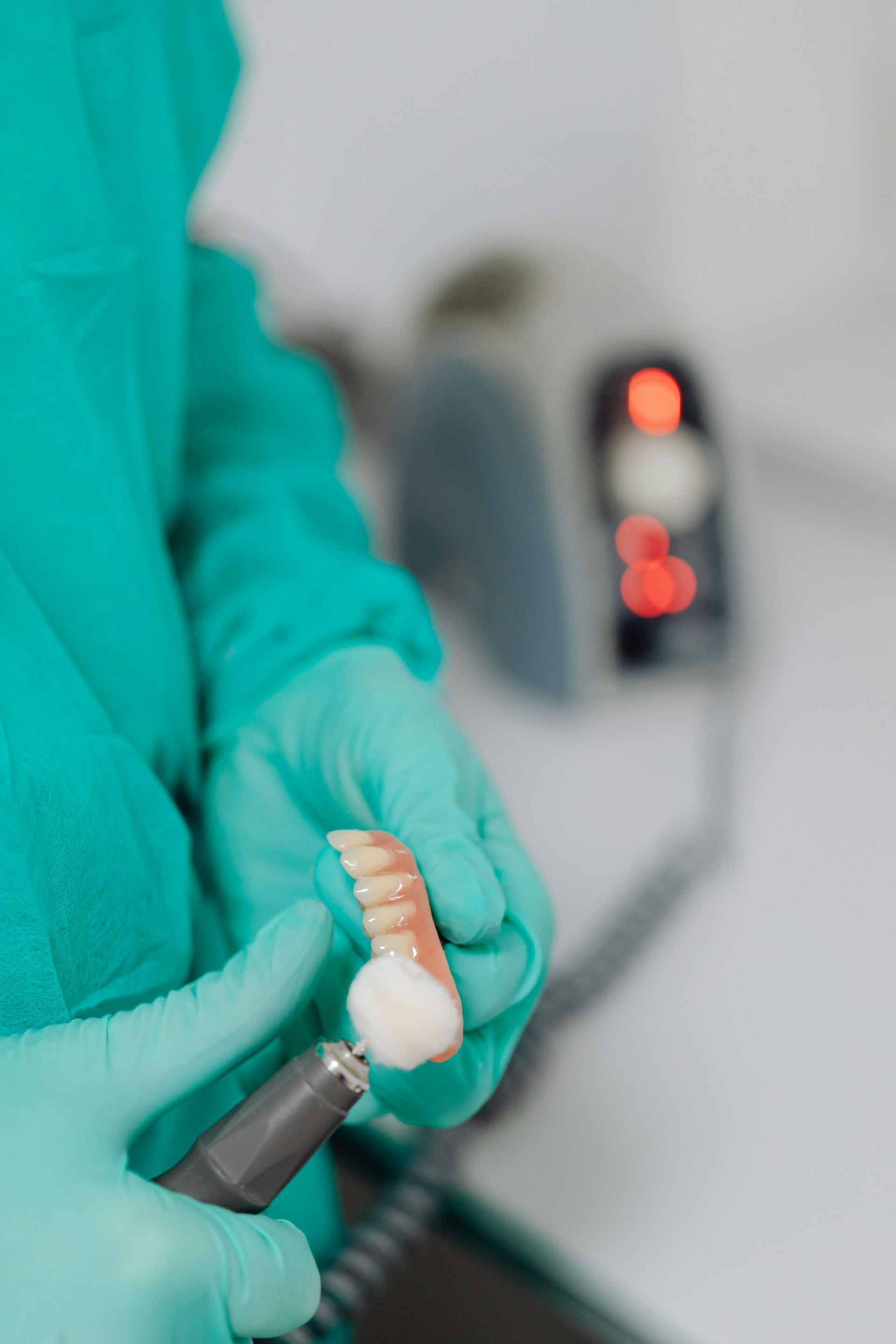 A Dentist Is Polishing A Denture With A Machine — Mittagong Dental Care In Mittagong, NSW