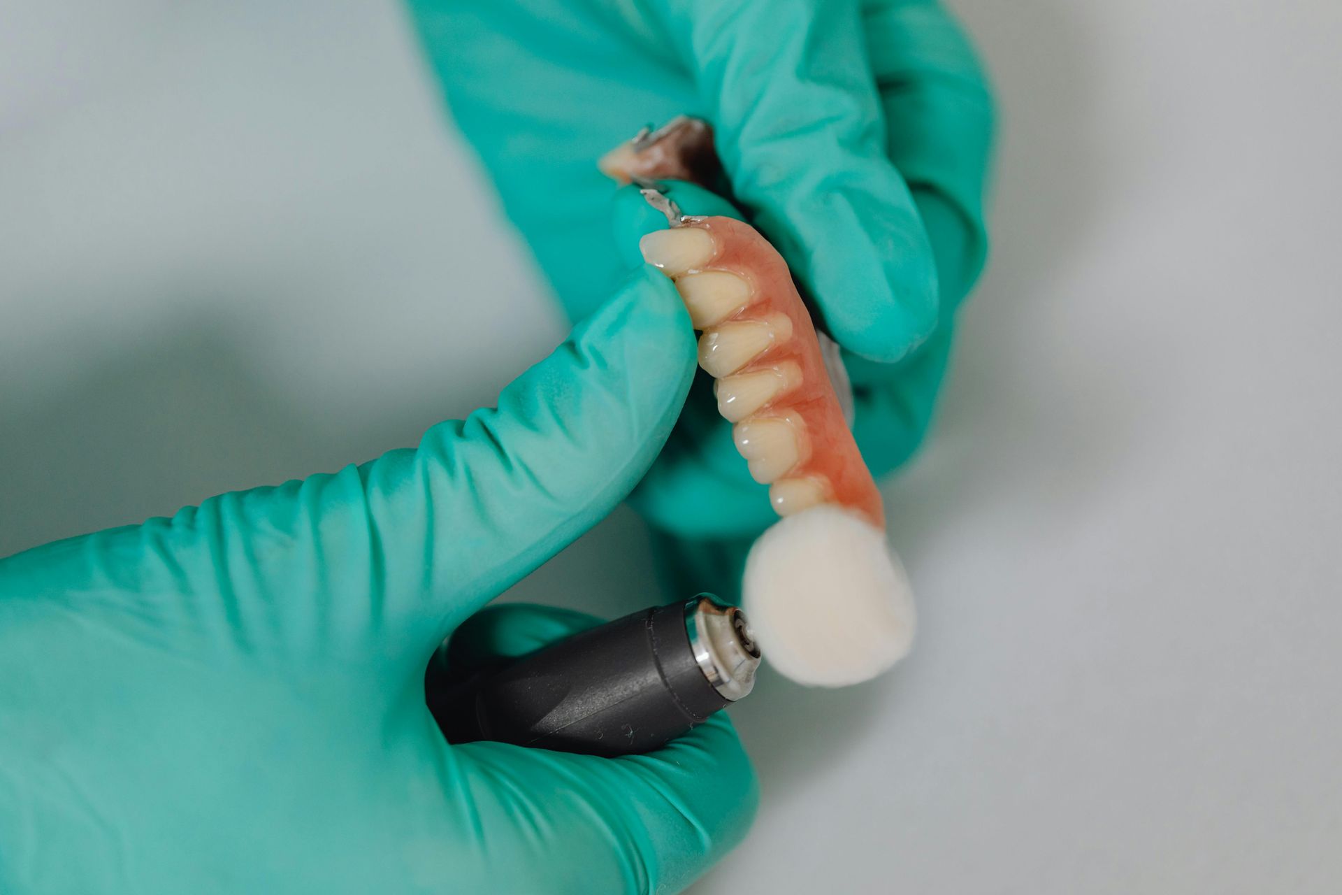 A Dentist Is Polishing A Denture With A Brush — Mittagong Dental Care In Mittagong, NSW