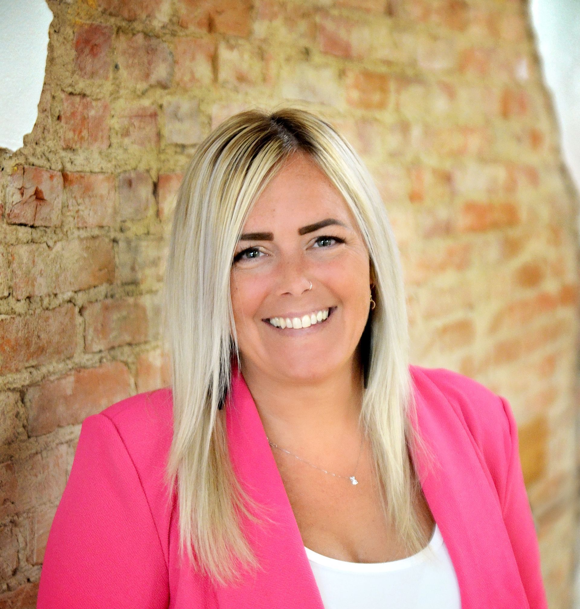 Hello! I'm Ashley Fisk, an insurance professional from the hometown of Lake Odessa. I have a passion for providing excellent customer service and educating clients on protection for what matters most. I have over 20 years’ experience in customer service and have been working in insurance for the last three years. My mission is to empower individuals to face the future with confidence, knowing they have a robust insurance strategy in place. I am eager to connect with individuals and businesses alike seeking expert advice on insurance matters. In my spare time, I enjoy baking, fishing, and spending time with my dog. Smiling woman in a bright pink blazer standing against a brick wall