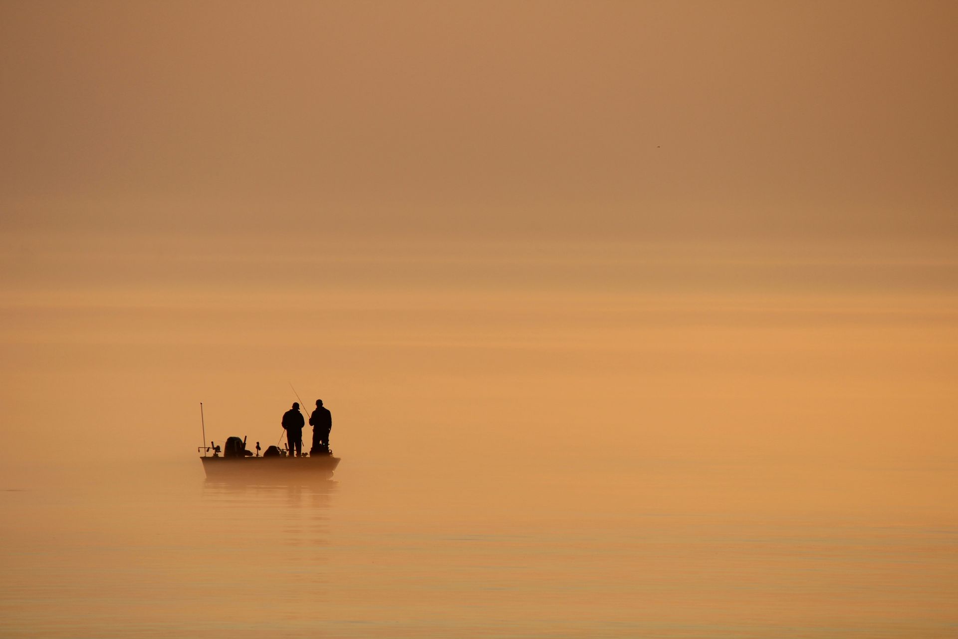 Two anglers fishing from a boat at sunrise on Lake Michigan near Sheboygan, Wisconsin
