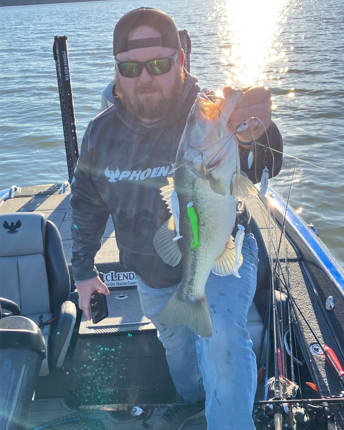 Person on a boat holding a large fish at sunset on the water