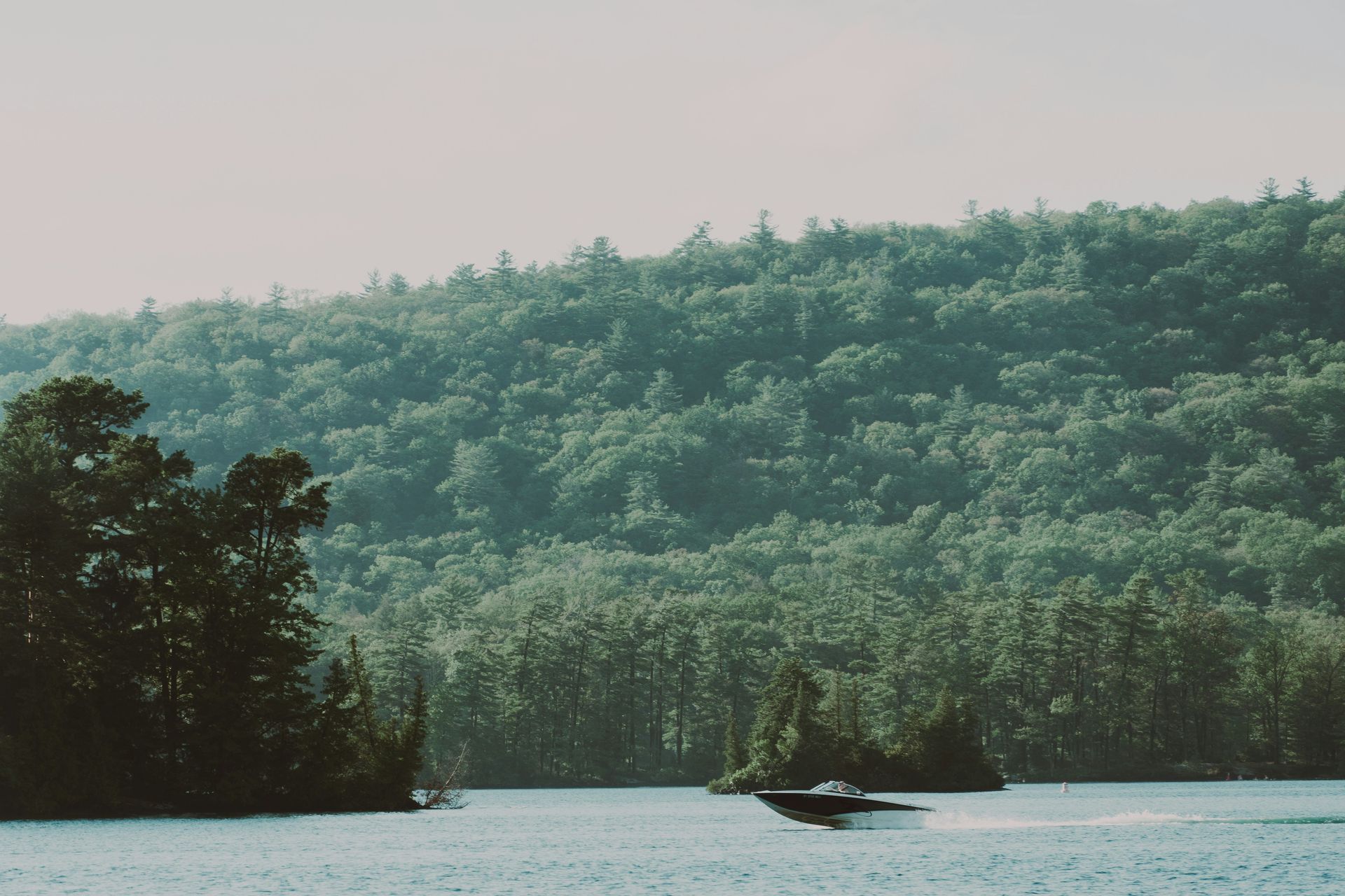 Boat on Lake George, New York, with a forested shoreline in the background