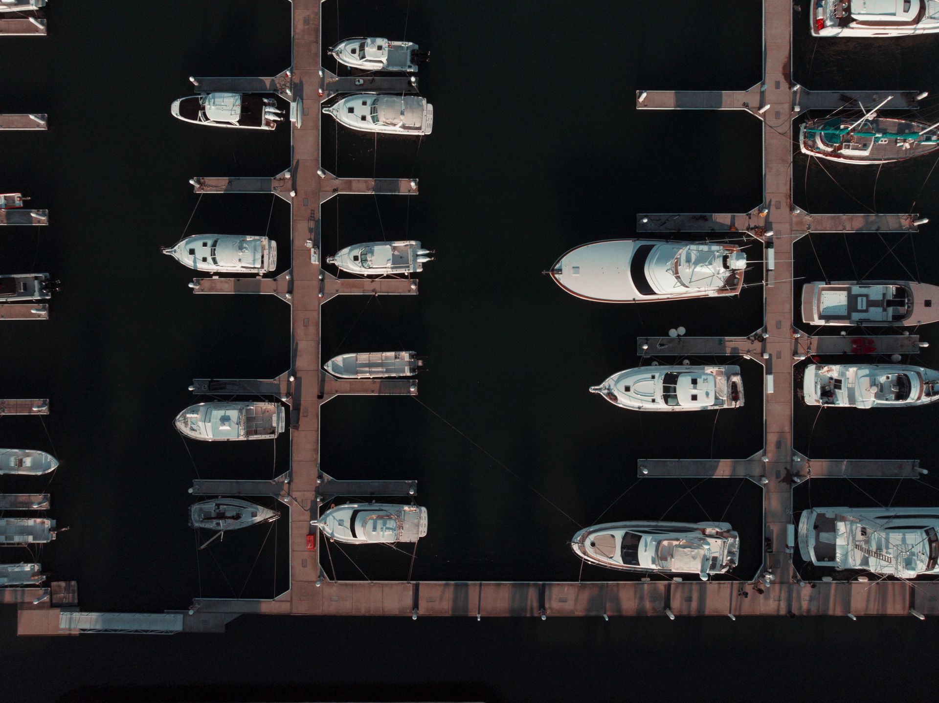 Aerial view of boats docked at a marina with wooden piers in dark water