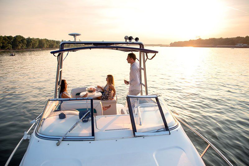 People relaxing on a boat at sunset on a calm lake, with golden light отражing on the water