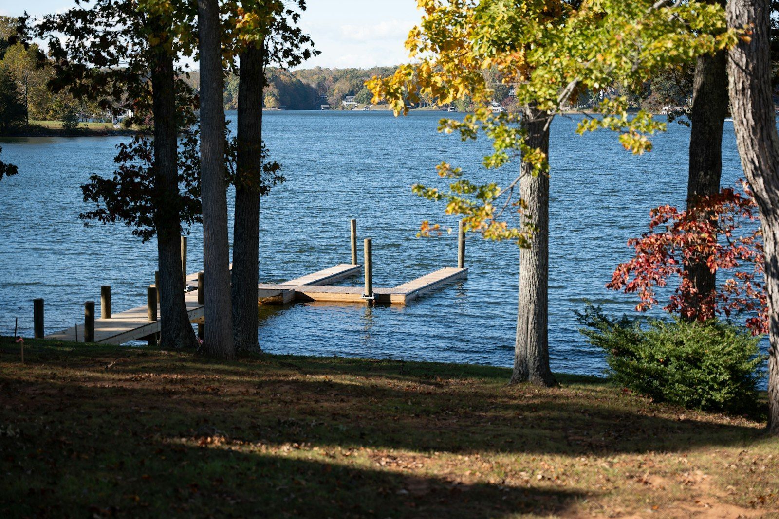 Wooden dock on Smith Mountain Lake, Virginia, with fall trees along the shore